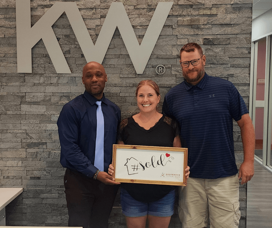 Clients holding a sold certificate at the Keller Williams office